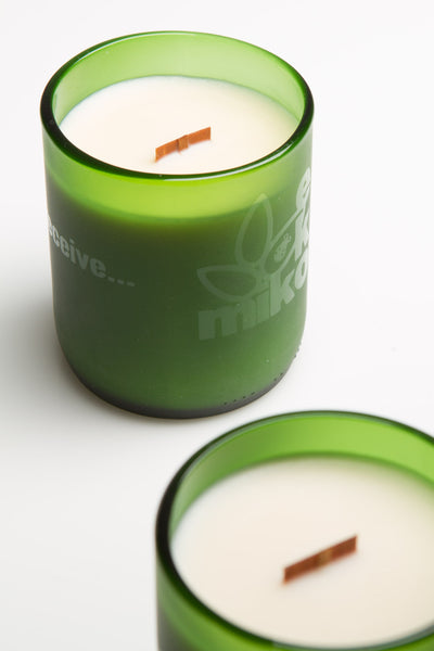 green candle containing coco butter wax. It has a wooden wick and EkoMiko logo.